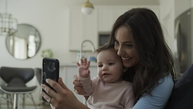 Mother with baby daughter video conferencing on cell phone / Bluffdale, Utah, United States