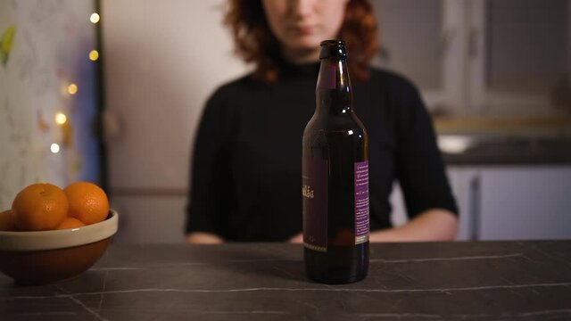 Young woman moves away bottle of beer as of quitting alcohol
