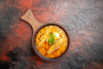 top view chicken soup in wooden bowl with handle on dark red background with copy space