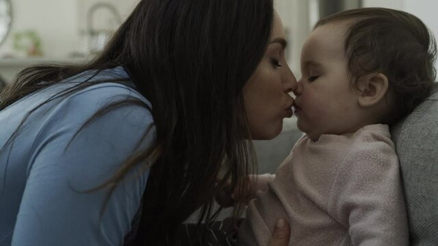Slow motion of mother making a face and kissing baby daughter / Bluffdale, Utah, United States