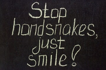 Fototapeta na wymiar Stop handsnakes, just smile on a dark chalk board. COVID lettering