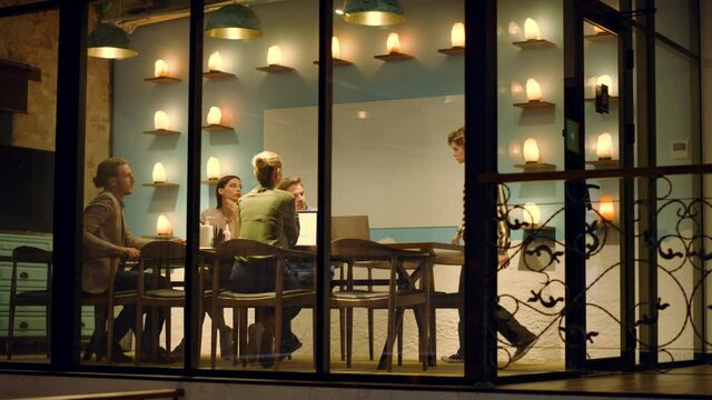 Creative team discussing ideas in glass wall office. Woman entering meeting room