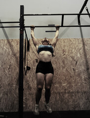 mujer colgada de la barra del gimnasio