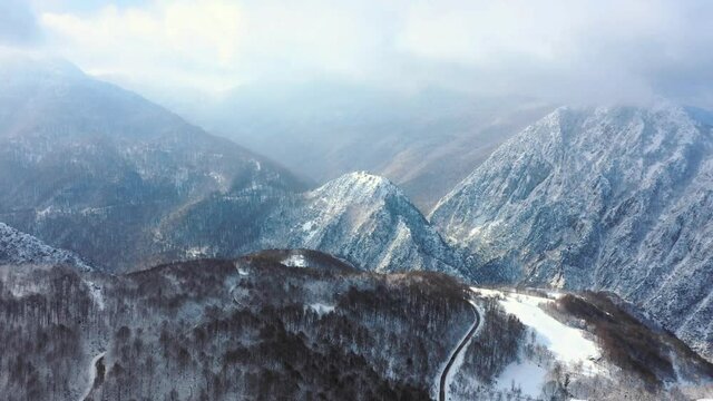 Aerial hyperzoom of Mountain ridges with forest in foreground. Snowy tree branches in a drone view of winter forest. Trees covered with frost and snow. Aerial winter landscape at Bolu, Turkey Country
