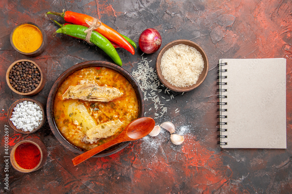 Wall mural top view bowl of chicken soup garlic bowl of rice dry spaghetti slices of bread on cutting board bow