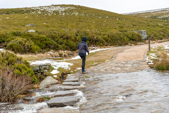 Woman jumping between some stones in order to cross a river