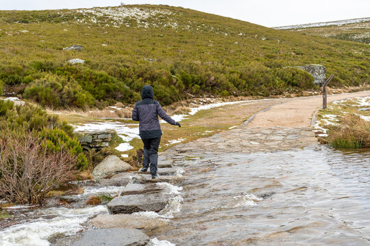 Woman jumping between some stones in order to cross a river