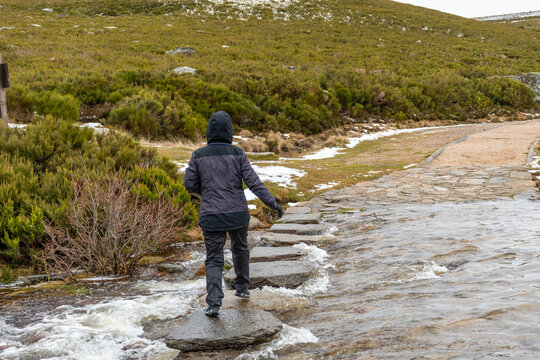 Horizontal view of a woman jumping between some stones in order to cross a river