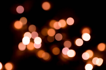 Bokeh lights background in yellow and lilac colors on black. Christmas lights string garland, festive overlay