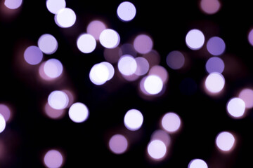 Bokeh lights background in yellow and lilac colors on black. Christmas lights string garland, festive overlay