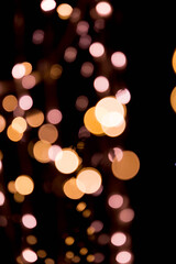 Bokeh lights background in yellow and lilac colors on black. Christmas lights string garland, festive overlay