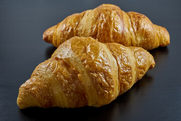 Freshly baked French croissants on a dark background.