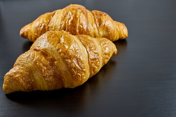 Freshly baked French croissants on a dark background.