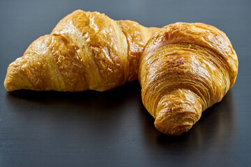 Freshly baked French croissants on a dark background.
