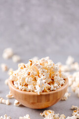 Delicios popcorn in a wooden bowl on a grey background
