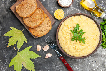 top view mashed potatoes bread slices on cutting board parsley lemon slices oil fork on dark background
