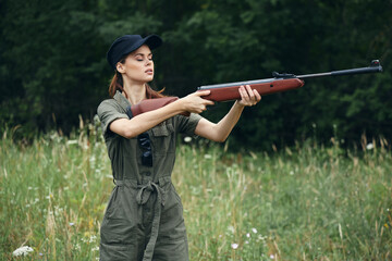 Woman on outdoor Holding a weapon in front of him hunting side views green leaves green 