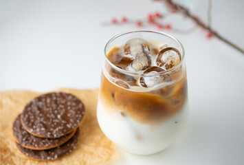 top view a glass of ice coffee with milk and chocchocolate biscuit on white table decorated with red fruit. refreshing cold drink in the summer  modern lifestyle relaxing hour in the afternoon at home