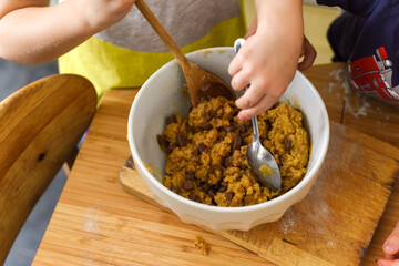 Children making food at home on a kitchen table they are mixing cookie dough