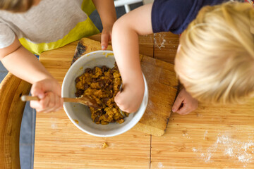 Children making food at home on a kitchen table they are mixing cookie dough