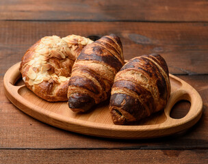 two baked croissants lie on a wooden tray