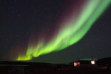 An undulating band of Northen lights snakes across the nightime sky in a remote location of the...