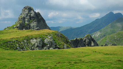 A sharp cliff pointed towards the sky standing on top of an alpine crest. Fagaras Massif provides a...