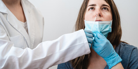 Doctor nurse worker taking nasal swab test for possible coronavirus infection - Focus in nose