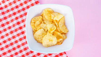 Bowl of home made potato pink background, top view