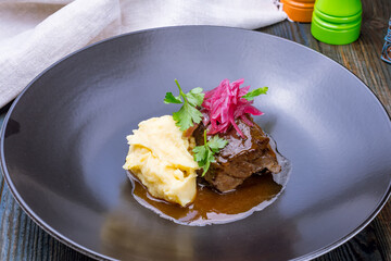 Beef cheeks with mashed potatoes on wooden table