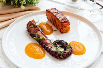 grilled octopus white on plate on white wooden table