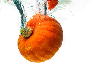 Orange pumpkin splashing into water isolated against white background. Healthy vegetables concept.