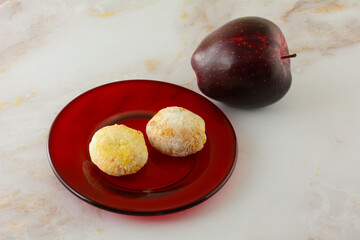German apple stollen cake bites on red glass plate with fresh raw red delicious apple on table