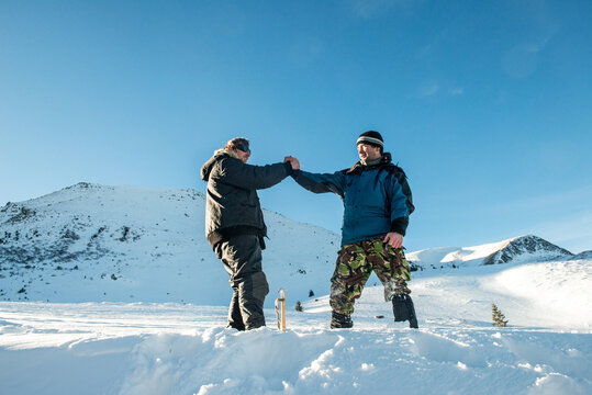 Handshake of two friends in the snowy mountains