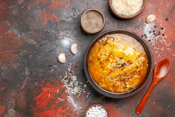 top view chicken soup bowls with pepper rice sea salt garlic spoon on dark red background with copy space