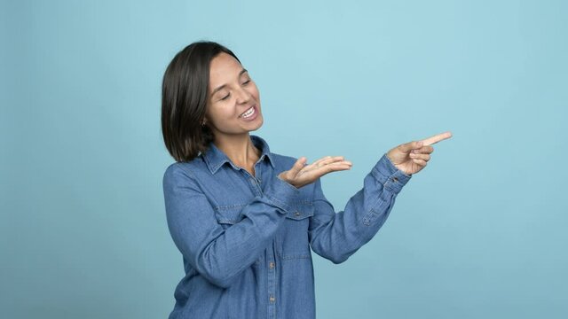 Young latin woman pointing finger to the side and presenting a product over isolated background