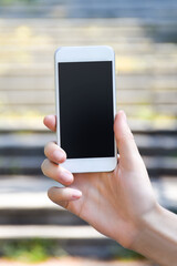 Close up of woman hold white smartphone in her hand with natural blur background.
