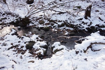 Partially frozen and snow covered creek in beautiful prír with icicles