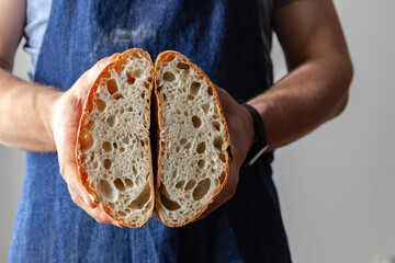 Baker dressed in an apron holds an Italian classic Ciabatta bread