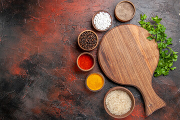 top view chopping board a bowl of rice different spices parsley on dark red background with copy space