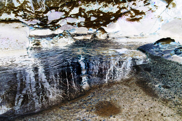 Obraz premium Inverted partially frozen and snow covered creek in beautiful prír with icicles