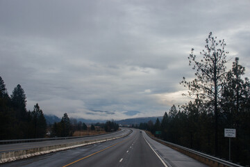 Highway with road signs on the sides among high mountains in the clouds in winter, along which trucks and cars travel. Idaho, USA, 12-5-2020