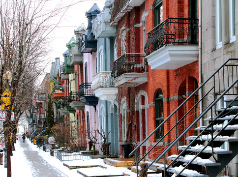 Beautiful houses of old historical Montreal neighborhood Plateau Mont Royal in winter season, bright painted doors and walls of expensive homes in gentrification-damaged area.