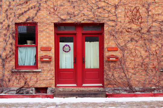 Typical beautiful house of old historical Montreal neighborhood Plateau Mont Royal in winter season, bright painted door with Christmas holiday decoration.