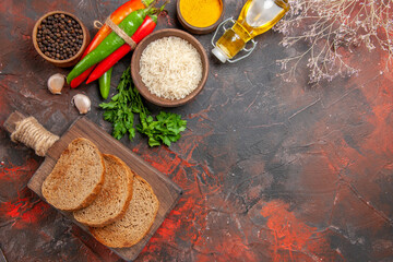 top view slices of bread on chopping board hot peppers bottle of oil parsley bowl of black pepper on dark red background with copy space