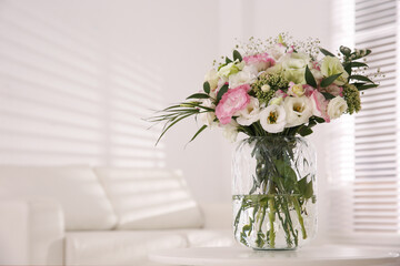 Fototapeta na wymiar Bouquet of beautiful flowers on table in living room, space for text. Interior design
