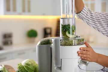 Young woman making tasty fresh juice in kitchen, closeup