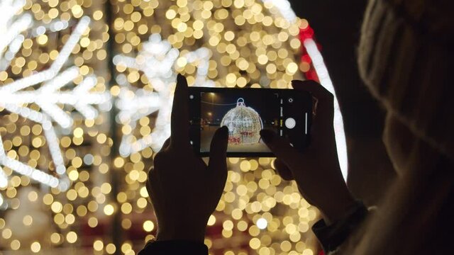 Person Taking Pictures with a Phone of a Christmas Lights at Night