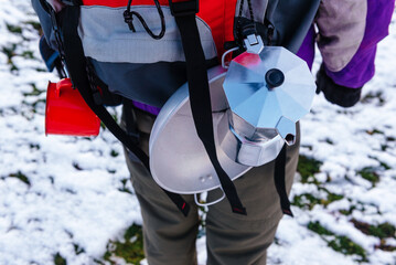 detail of a camper's backpack with camping and mountain utensils. coffee pot and camping plate Red backpack.