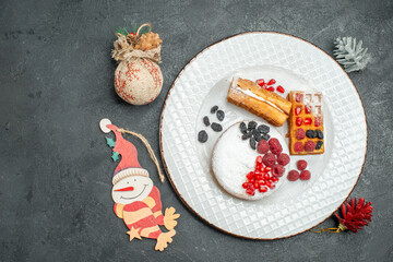 top view plate with berry tart and waffles and paper xmas pendants on dark background with copy space